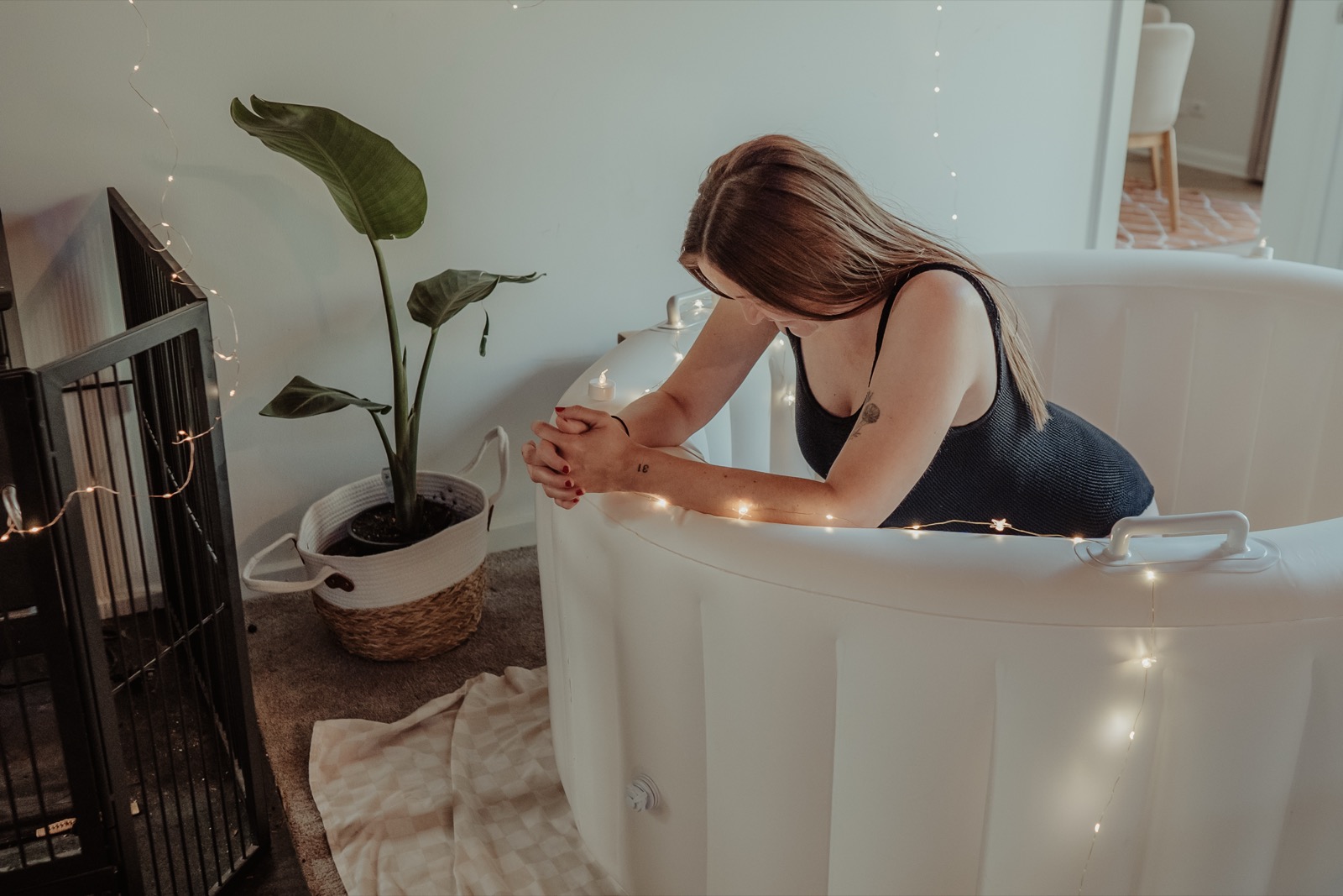 Pregnant woman labouring in the white birth pool surrounded by fairy lights
