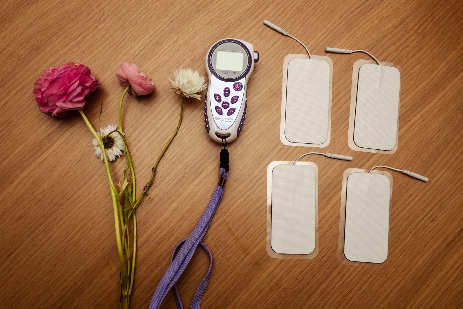ELLETENS 2 TENS machine with flowers on a wooden surface